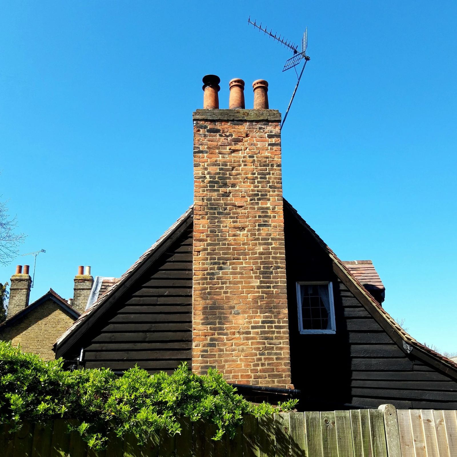 Souche de cheminée en briques sur un toit ancien, sous un ciel bleu